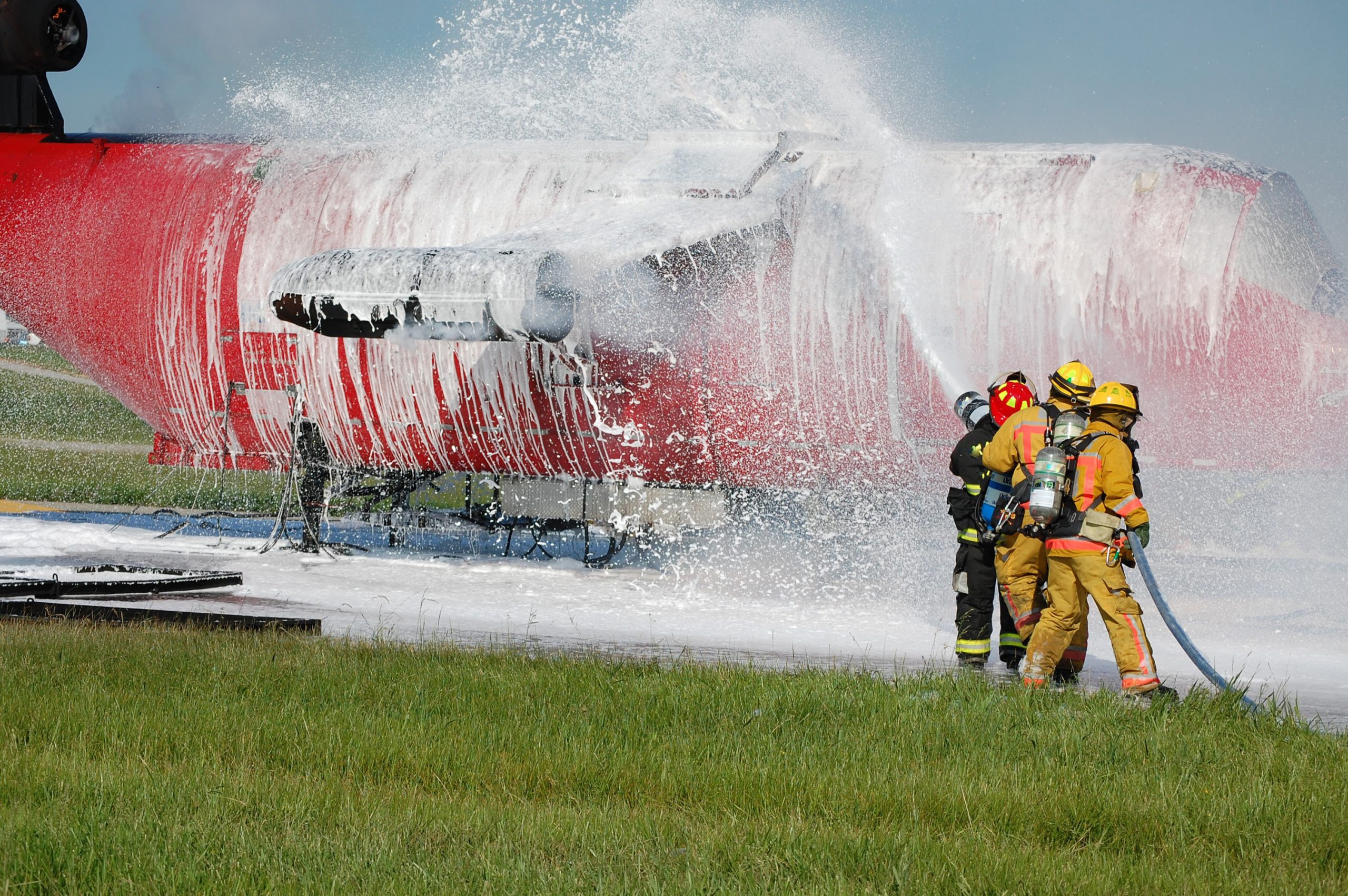 Firefighters spray an airplane with firefighting foam.